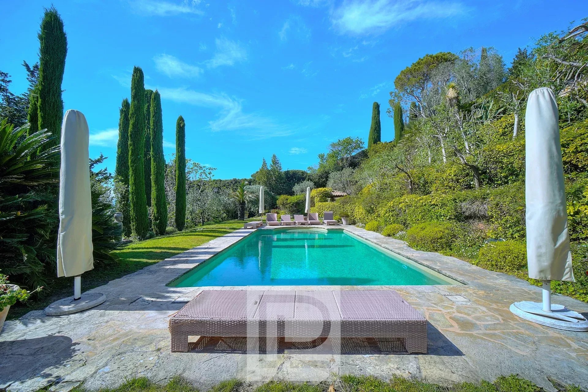 Piscine entourée de verdure dans une villa à Mougins avec vue panoramique sur la mer et l'arrière-pays.