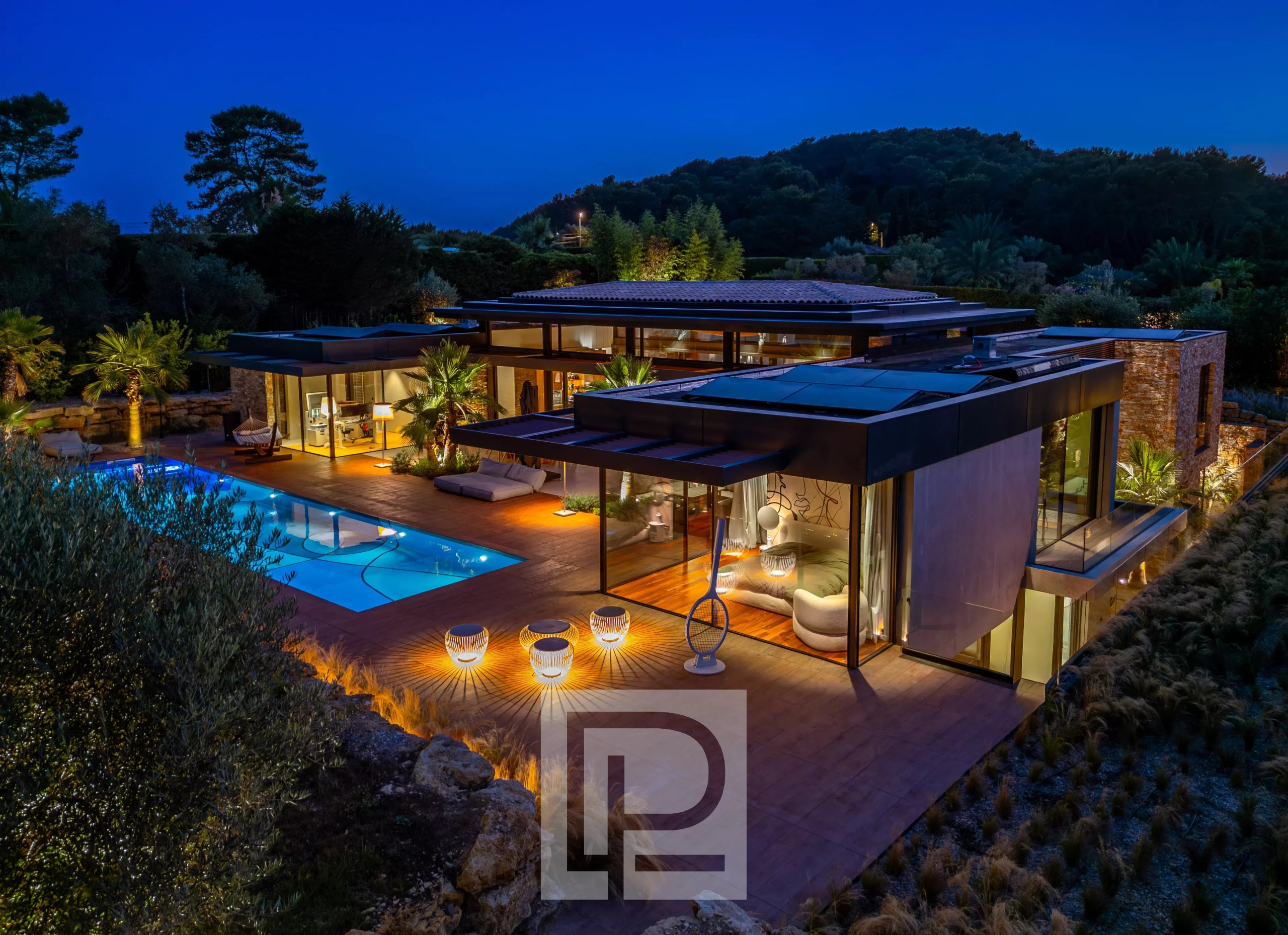 Contemporary property in Mougins Contemporary villa with swimming pool in Mougins, lit up at night, surrounded by greenery.