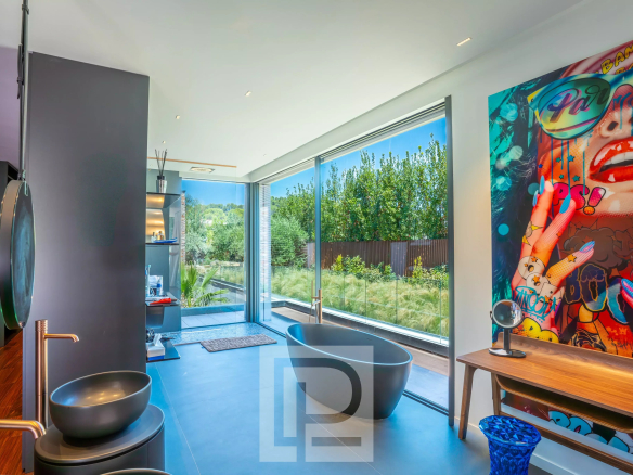 Modern bathroom with bathtub, garden view, artistic decoration in Mougins.