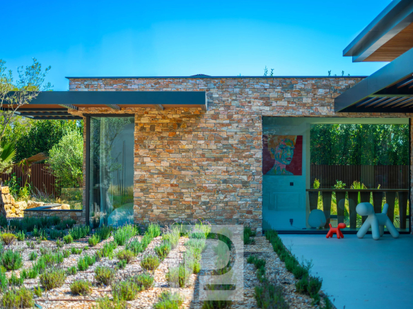 Exterior view of a contemporary villa with stone walls and a landscaped garden in Mougins.
