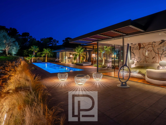 Contemporary villa with swimming pool and outdoor spaces in Mougins, lit up at night.