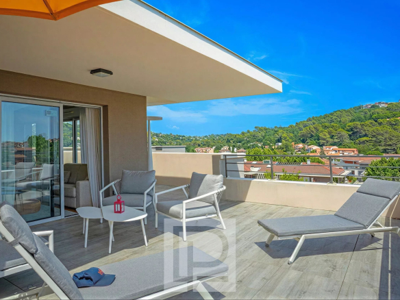 Terrasse d'un appartement moderne avec chaises longues et vue sur les collines à Mougins.