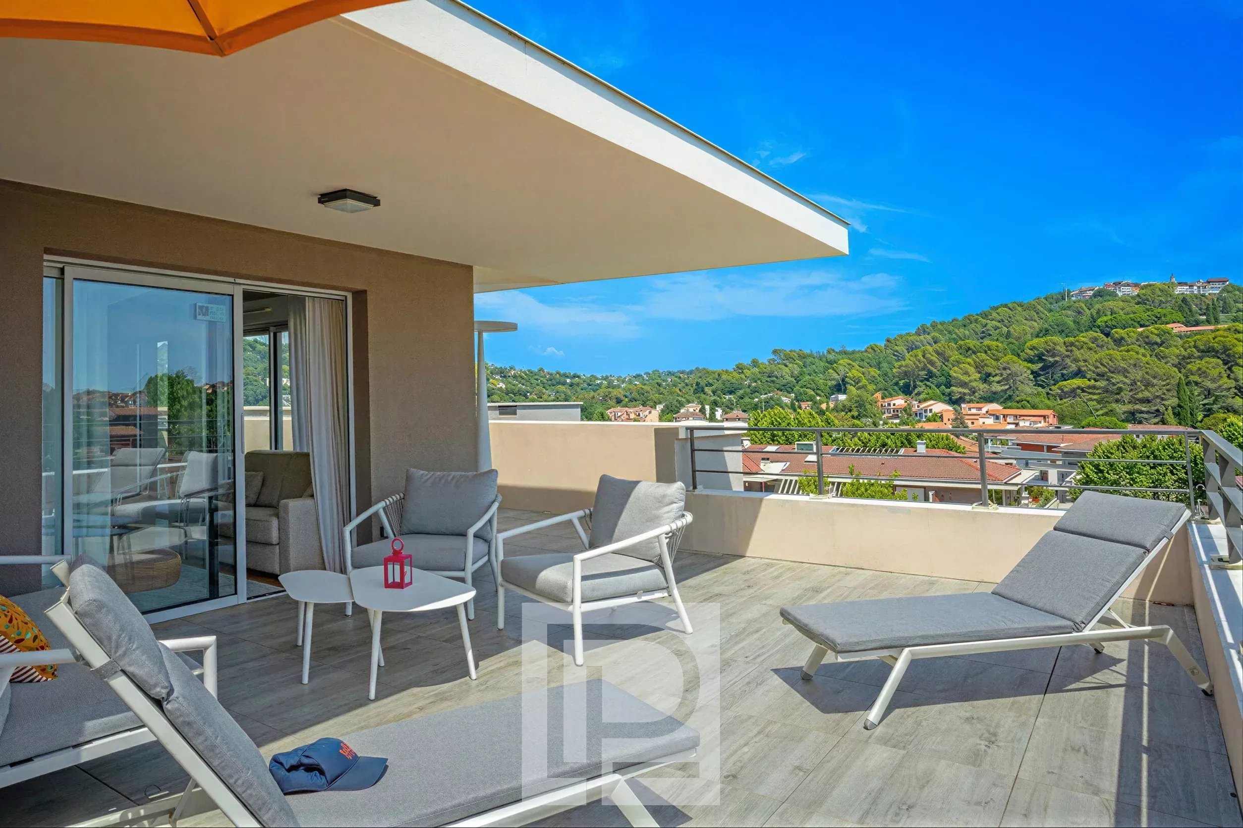 Terrasse d'un appartement moderne avec chaises longues et vue sur les collines à Mougins.