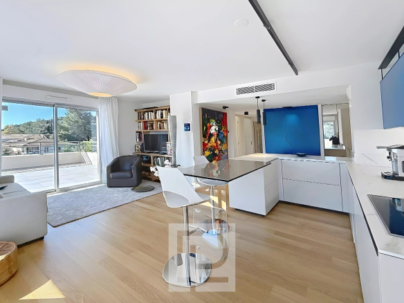 Intérieur d'un appartement moderne avec cuisine ouverte et salon, vue sur la terrasse.
