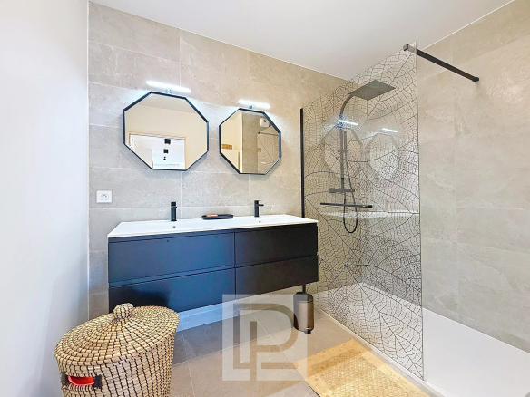 Salle de bain moderne avec douche à l'italienne et double vasque dans un appartement à Mougins.
