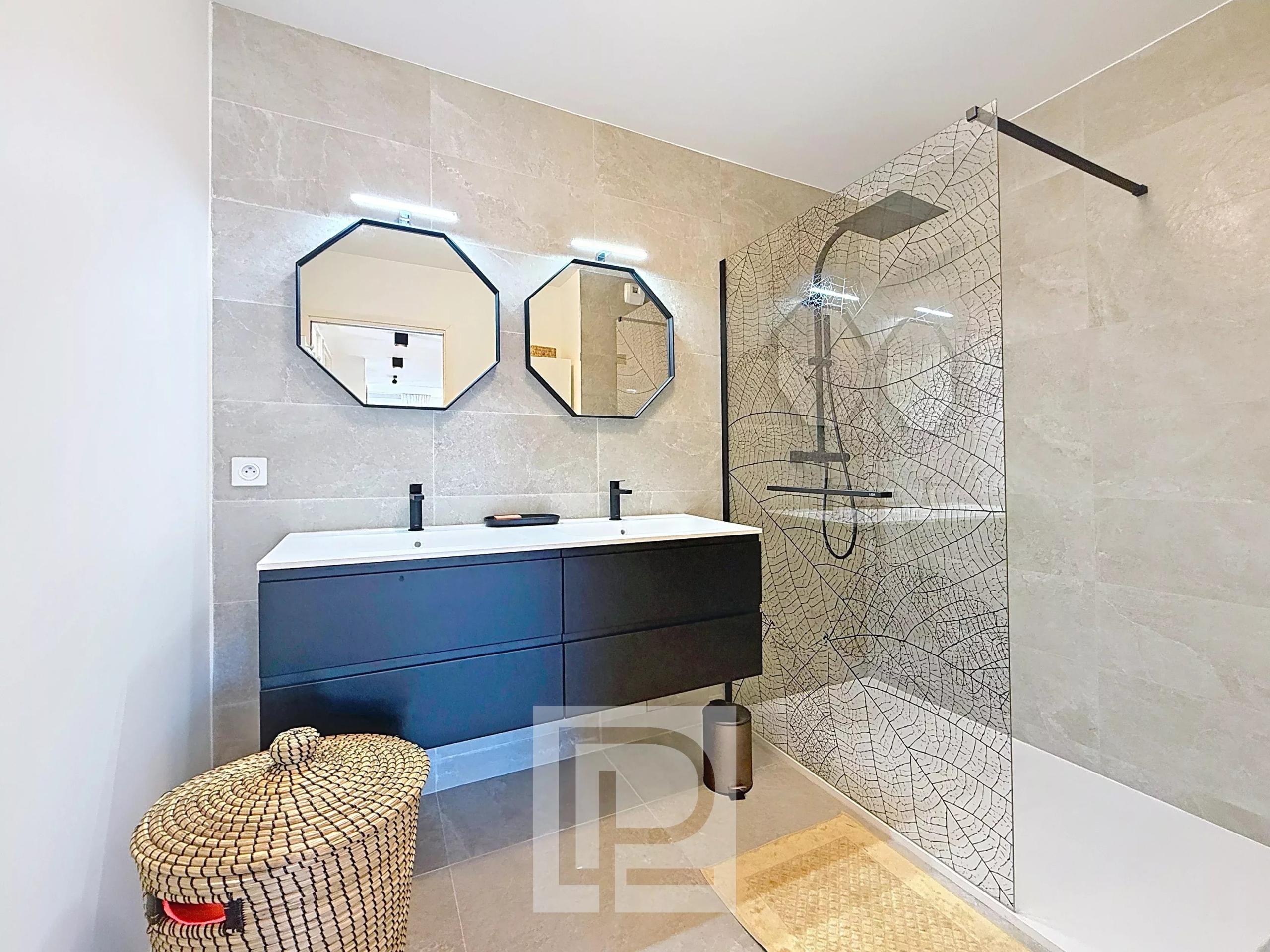 Salle de bain moderne avec douche à l'italienne et double vasque dans un appartement à Mougins.