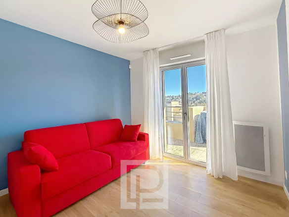Salon d'un appartement moderne avec canapé rouge et accès à un balcon.