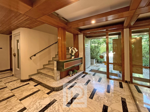 Entrance hall of a renovated apartment with a staircase and glass doors leading to a garden.