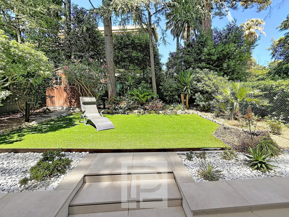 Private garden of a renovated apartment in Cannes with lawn and landscaping.