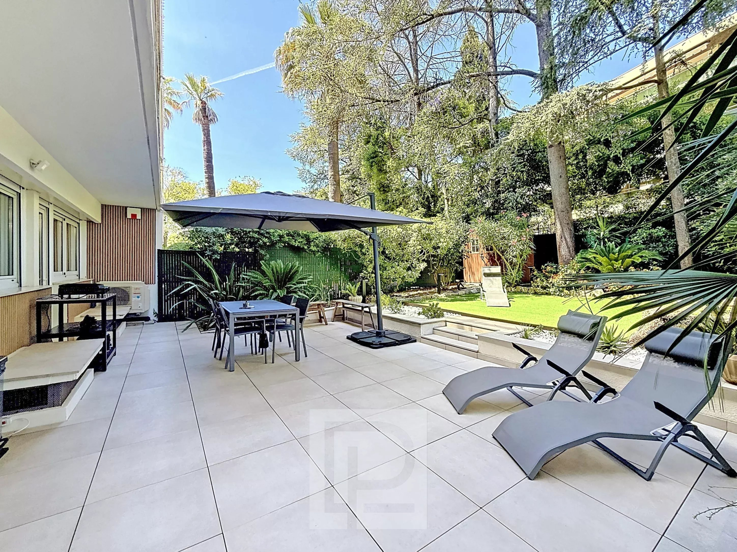 Terrace and garden of an apartment in Cannes Terrace of a renovated apartment with garden in Cannes, garden furniture and parasol.