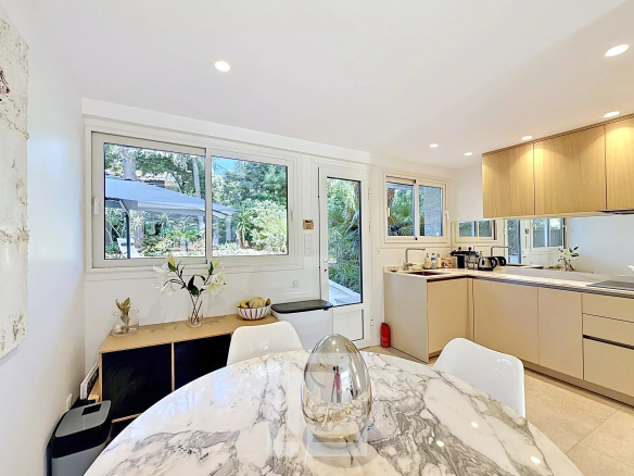 Interior of a renovated apartment with modern kitchen and garden view in Cannes.
