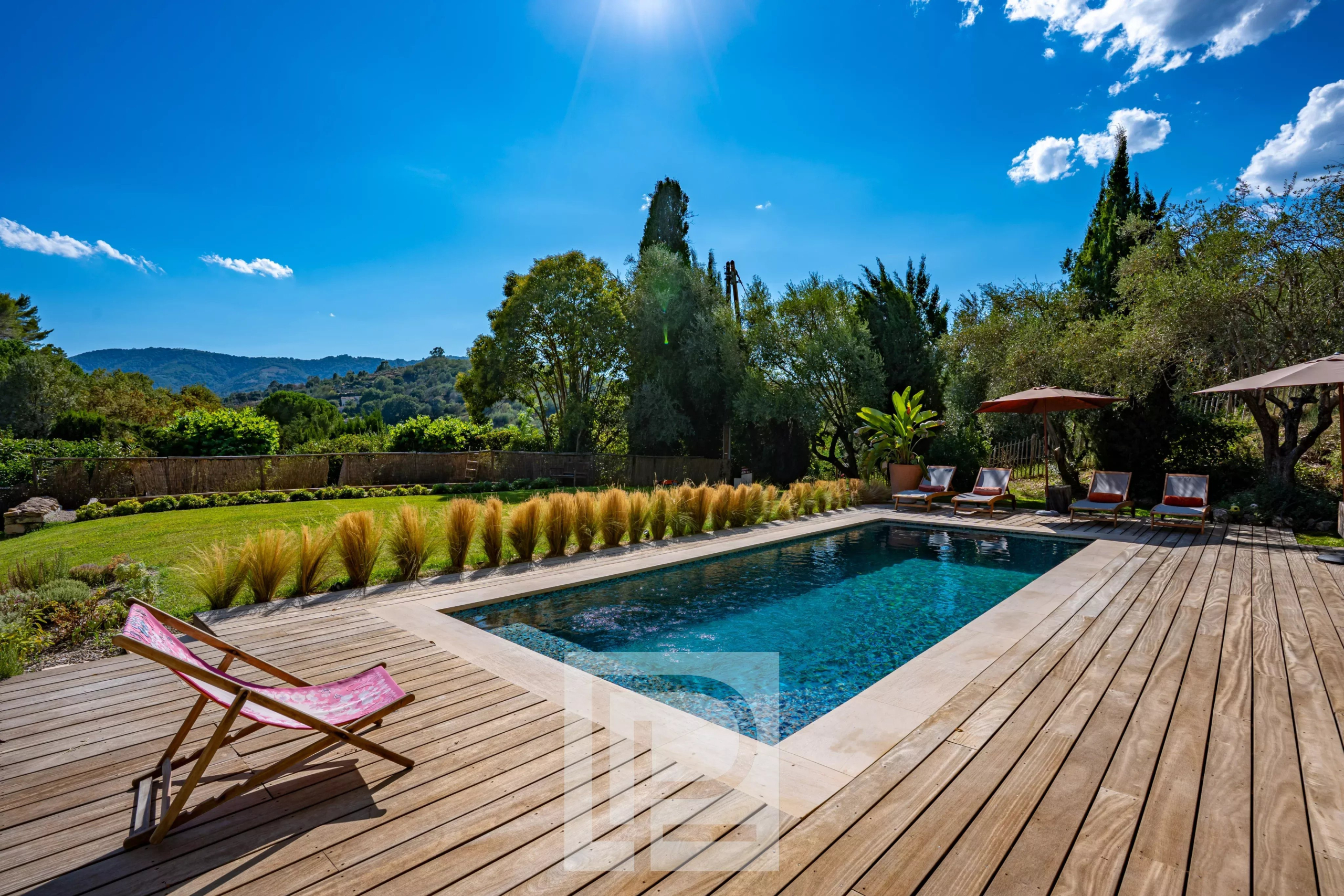 Bastide rénovée avec piscine à Pégomas Piscine entourée de chaises longues et de verdure dans une bastide rénovée à Pégomas.