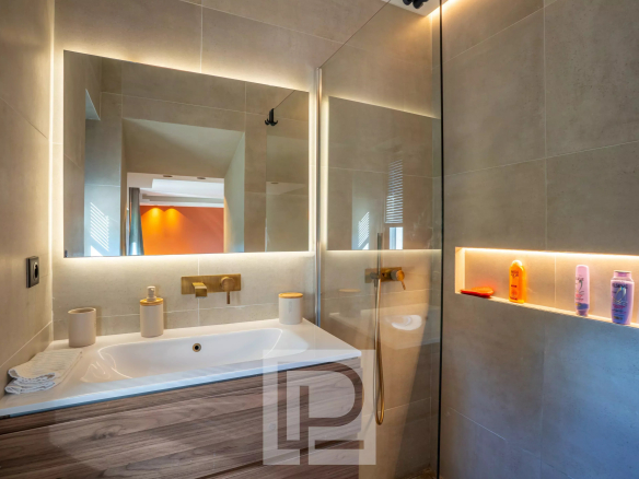 Salle de bain moderne avec baignoire, miroir et éclairage, dans une bastide rénovée.