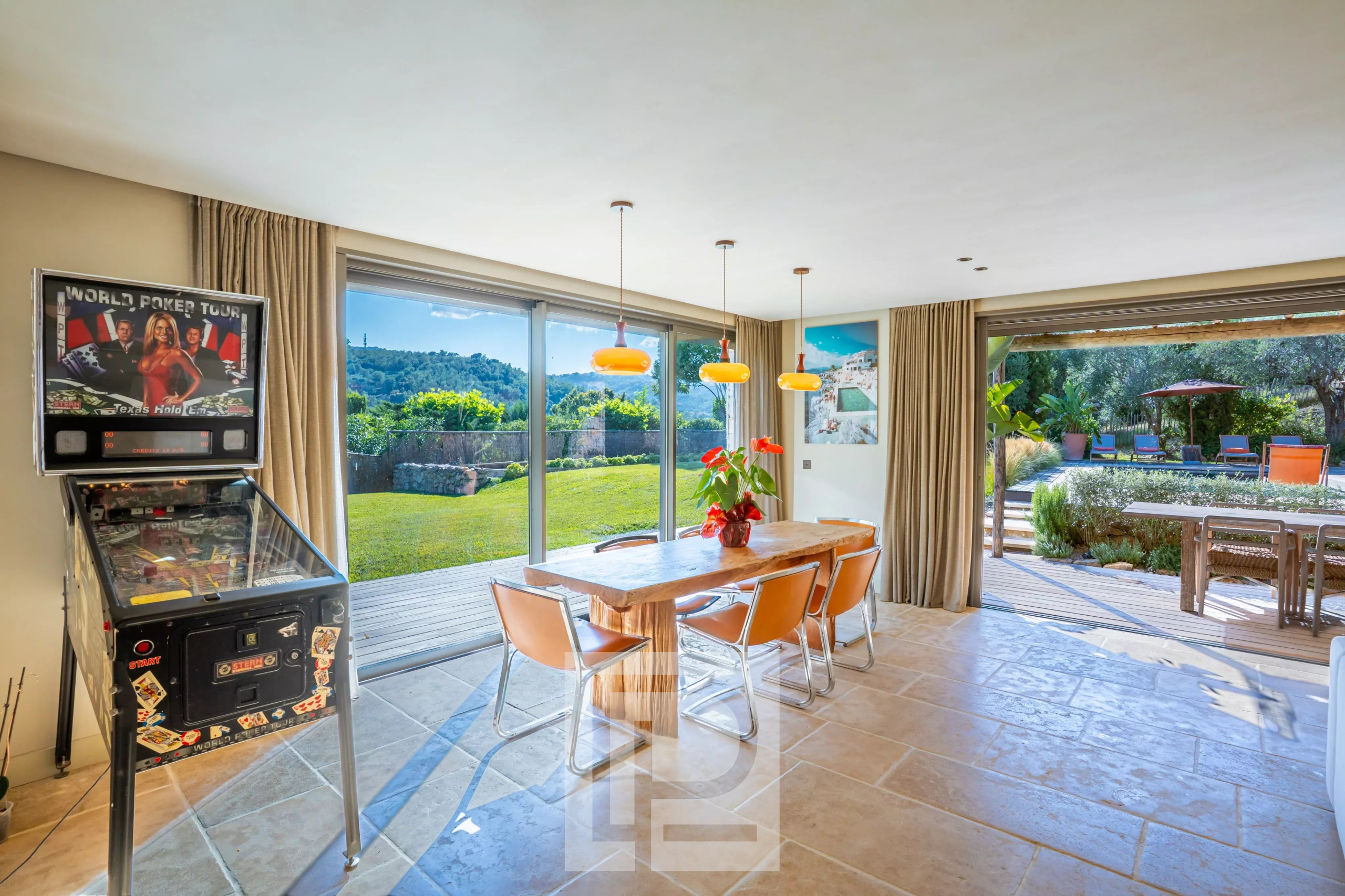 Intérieur d’une bastide à Pégomas Intérieur d'une bastide rénovée avec vue sur la nature, table en bois et machine à flipper.