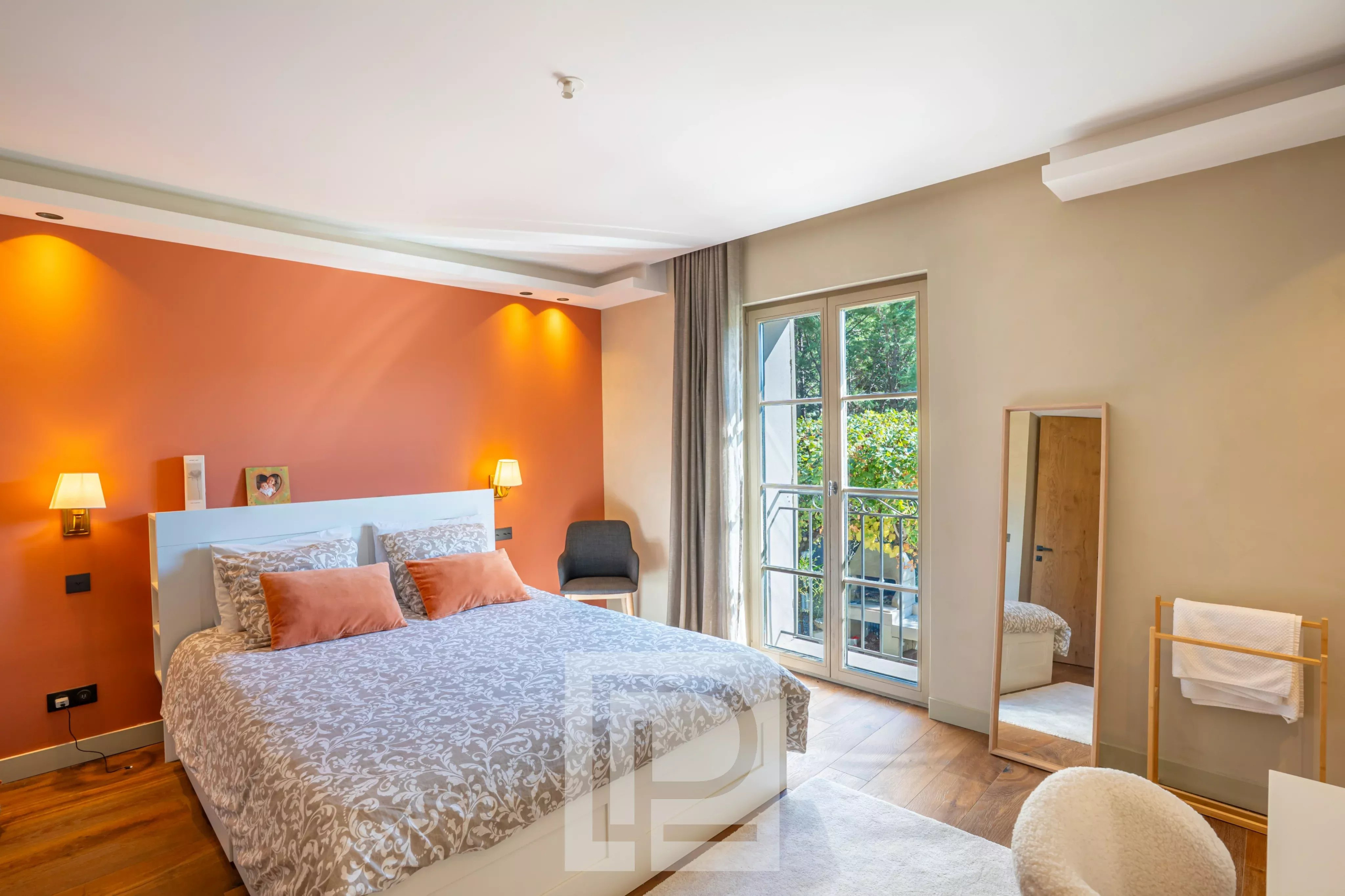 Chambre de bastide rénovée à Pégomas Chambre d'une bastide rénovée avec lit double, murs orange et accès à un balcon.