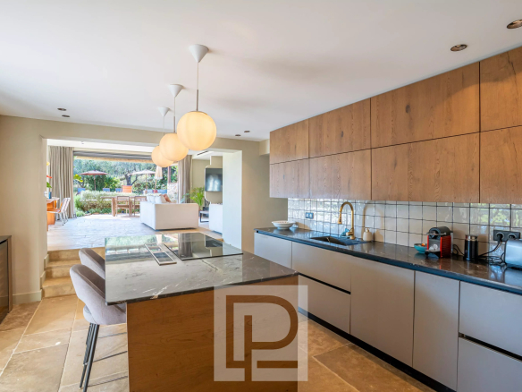 Intérieur d'une cuisine moderne avec un îlot central et un accès à une terrasse extérieure.