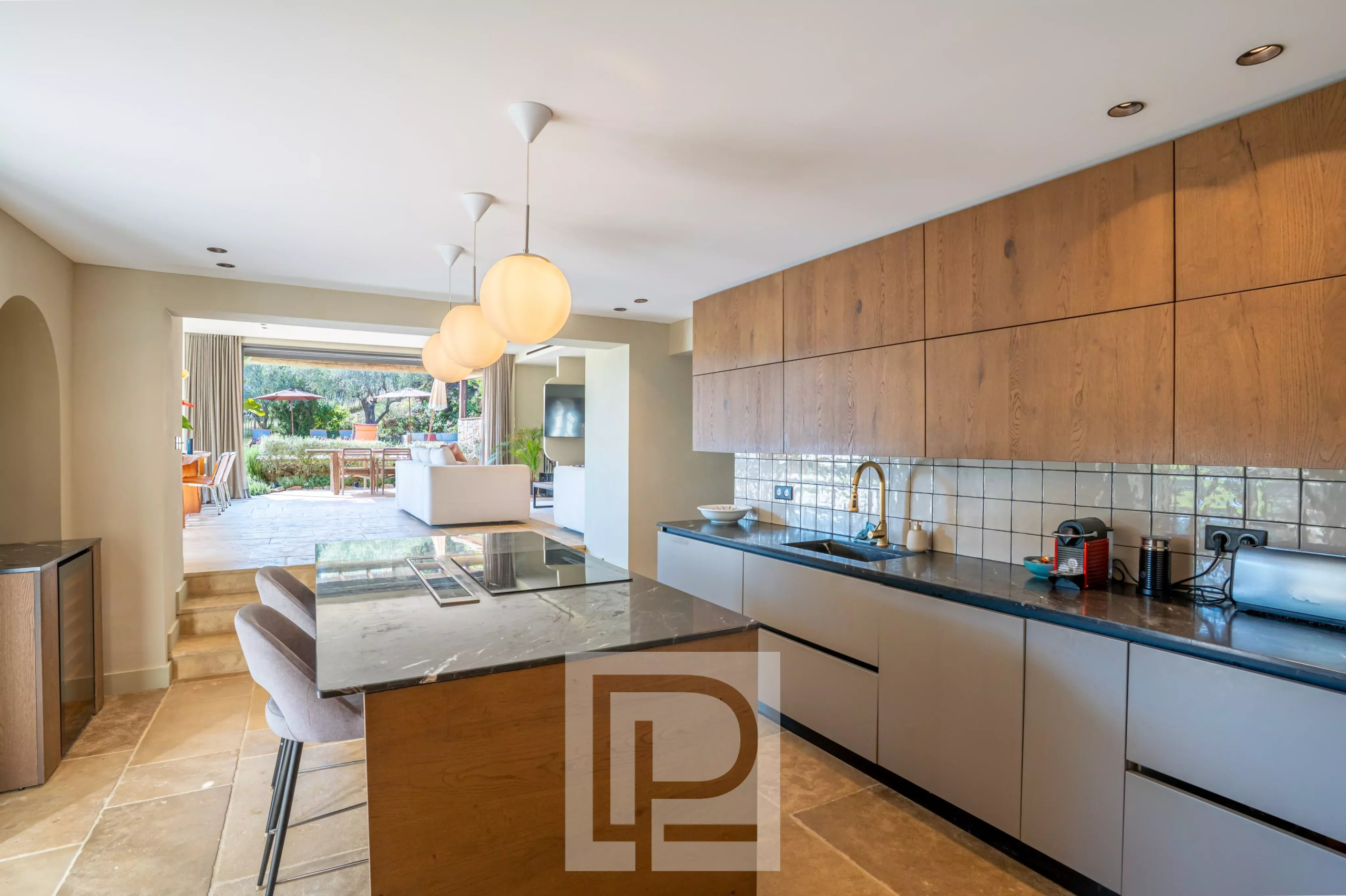 Cuisine rénovée d’une bastide à Pégomas Intérieur d'une cuisine moderne avec un îlot central et un accès à une terrasse extérieure.