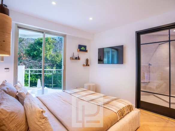 Chambre d'appartement rénové avec vue sur la verdure à Cannes, incluant salle de bain attenante.