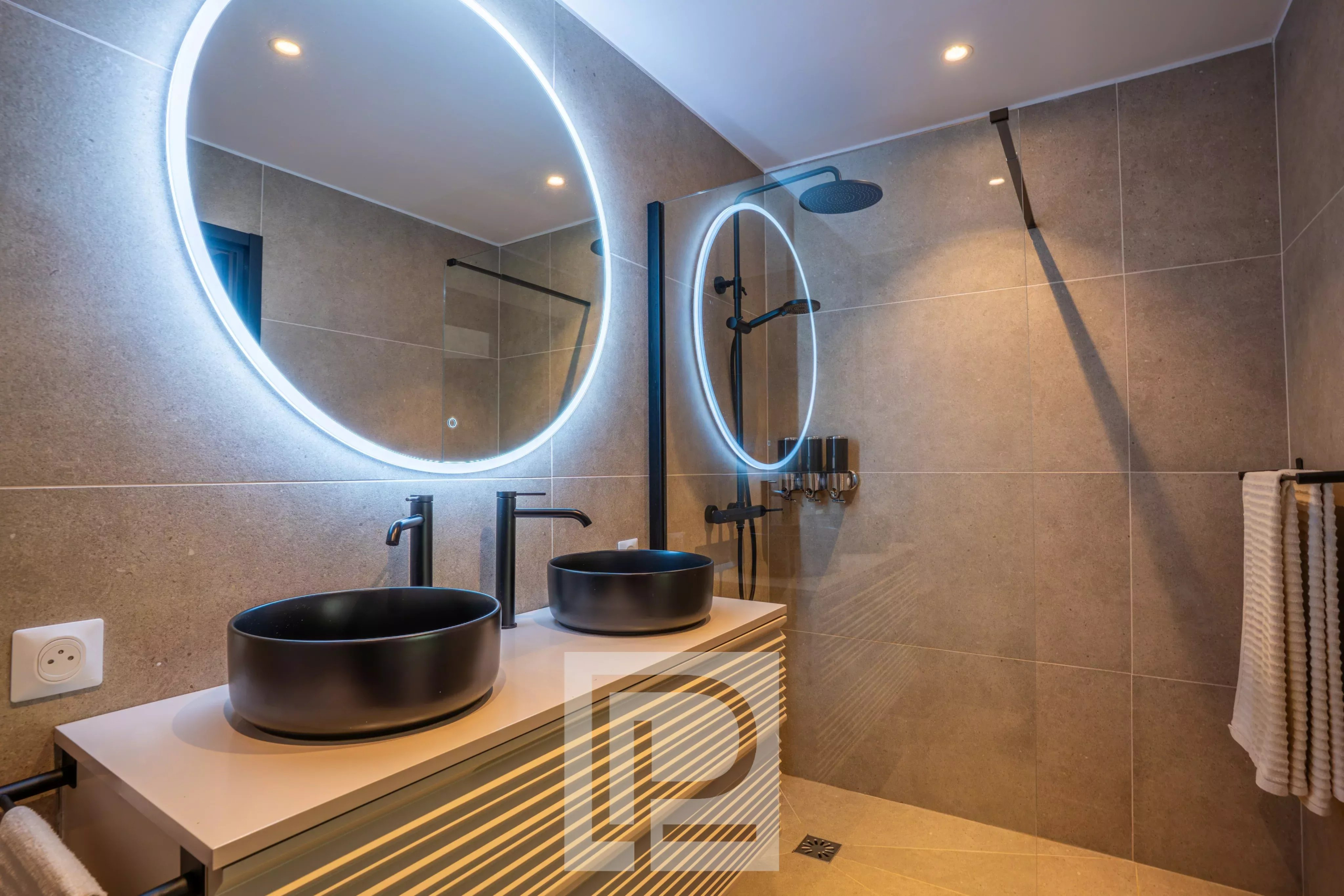 Salle de bain rénovée au design contemporain Salle de bain moderne avec deux lavabos et miroirs ronds lumineux.