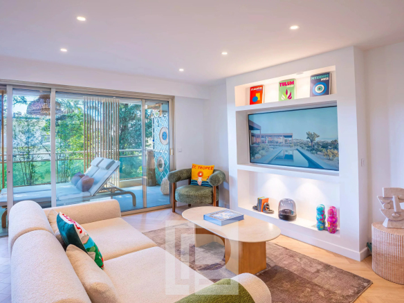 Salon d'un appartement rénové à Cannes avec vue sur le jardin, mobilier moderne et lumineux.