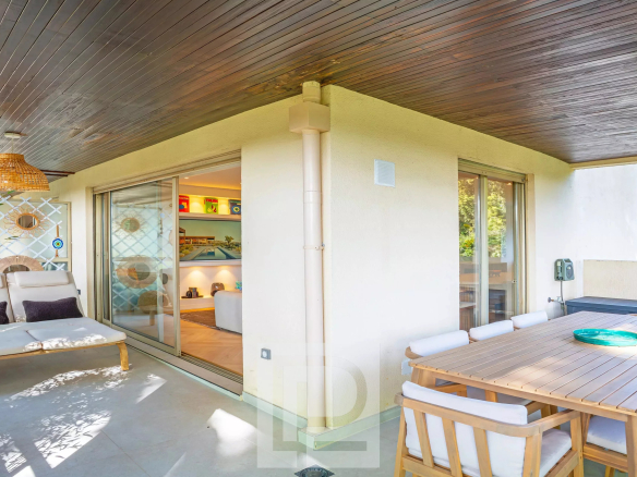 Terrasse d'un appartement rénové à Cannes avec mobilier moderne et verdure environnante.