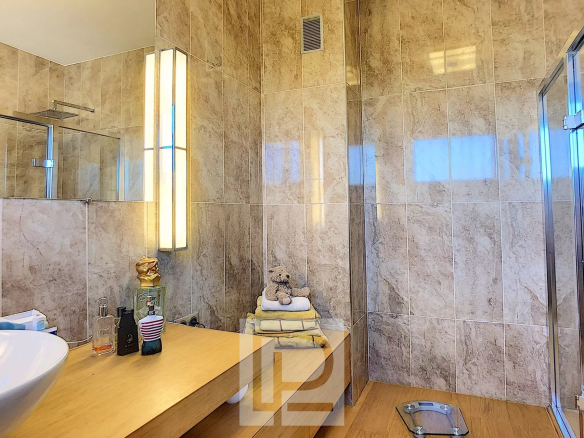 Modern bathroom with shower, sink and marble decor.