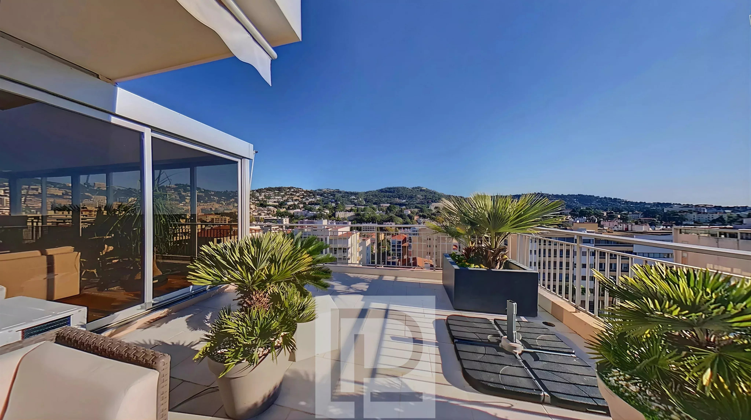 Rooftop with a view in Le Cannet Rooftop of an apartment with views of the hills, potted plants and outdoor furniture.