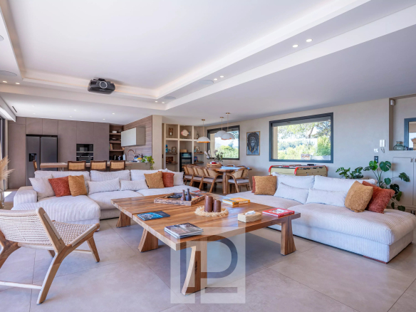 Intérieur d'une villa rénovée avec salon spacieux et cuisine ouverte, vue sur la mer.
