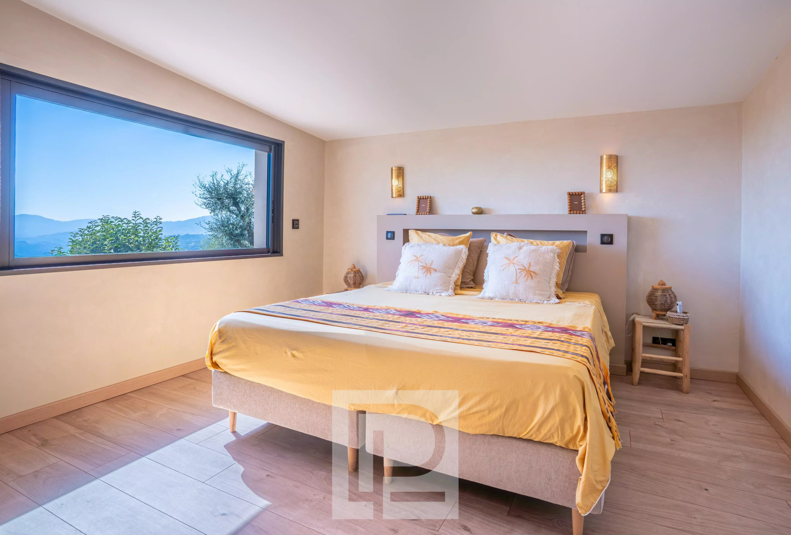 Chambre d'une villa rénovée avec vue sur la mer à Mougins, murs clairs et lit double.