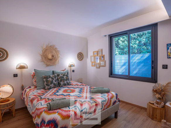 Chambre d'une villa rénovée avec décoration colorée et fenêtre donnant sur l'extérieur.