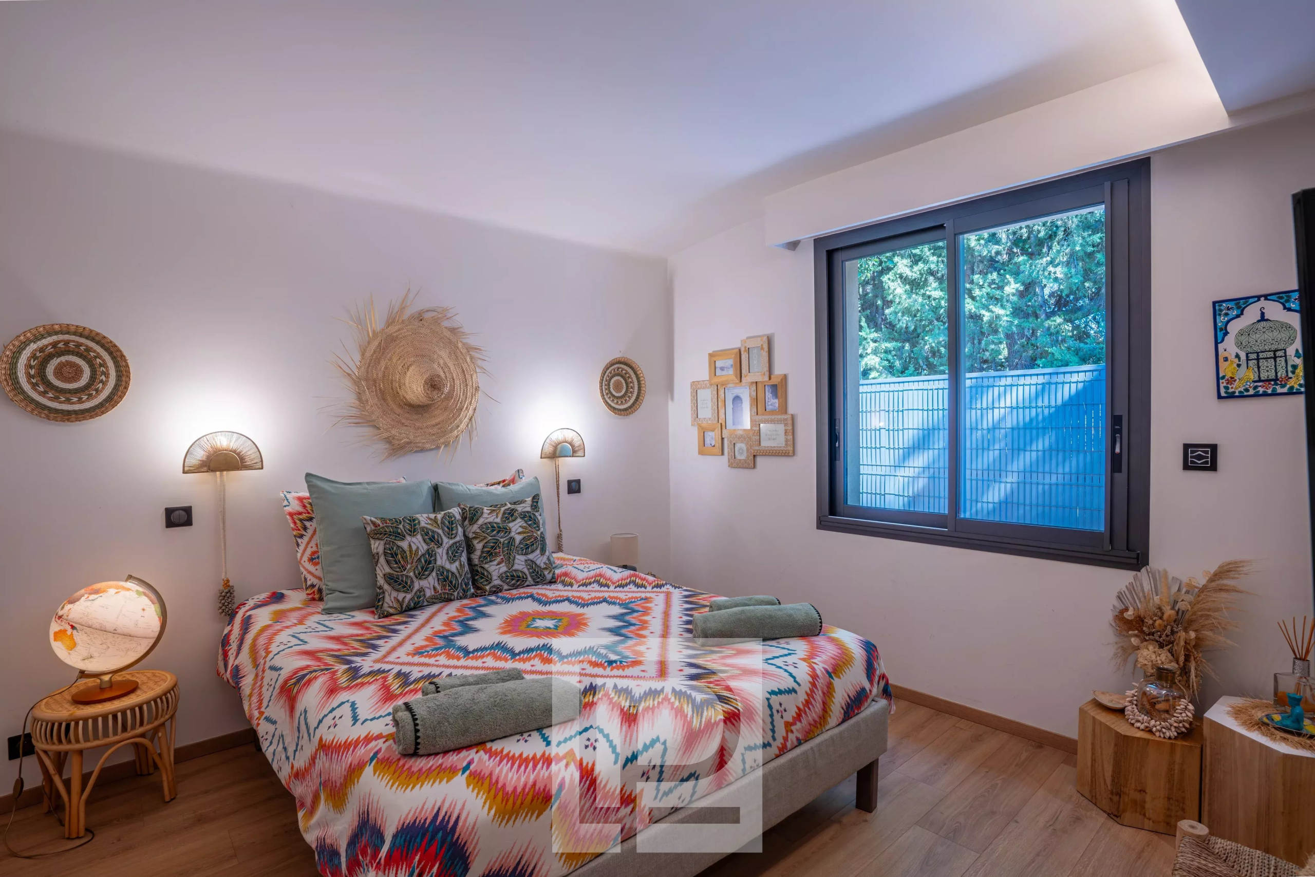 Chambre d'une villa rénovée avec décoration colorée et fenêtre donnant sur l'extérieur.