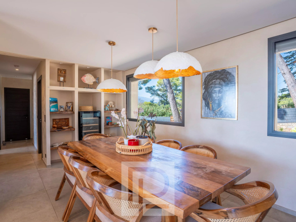 Salle à manger d'une villa rénovée avec table en bois et luminaires modernes.