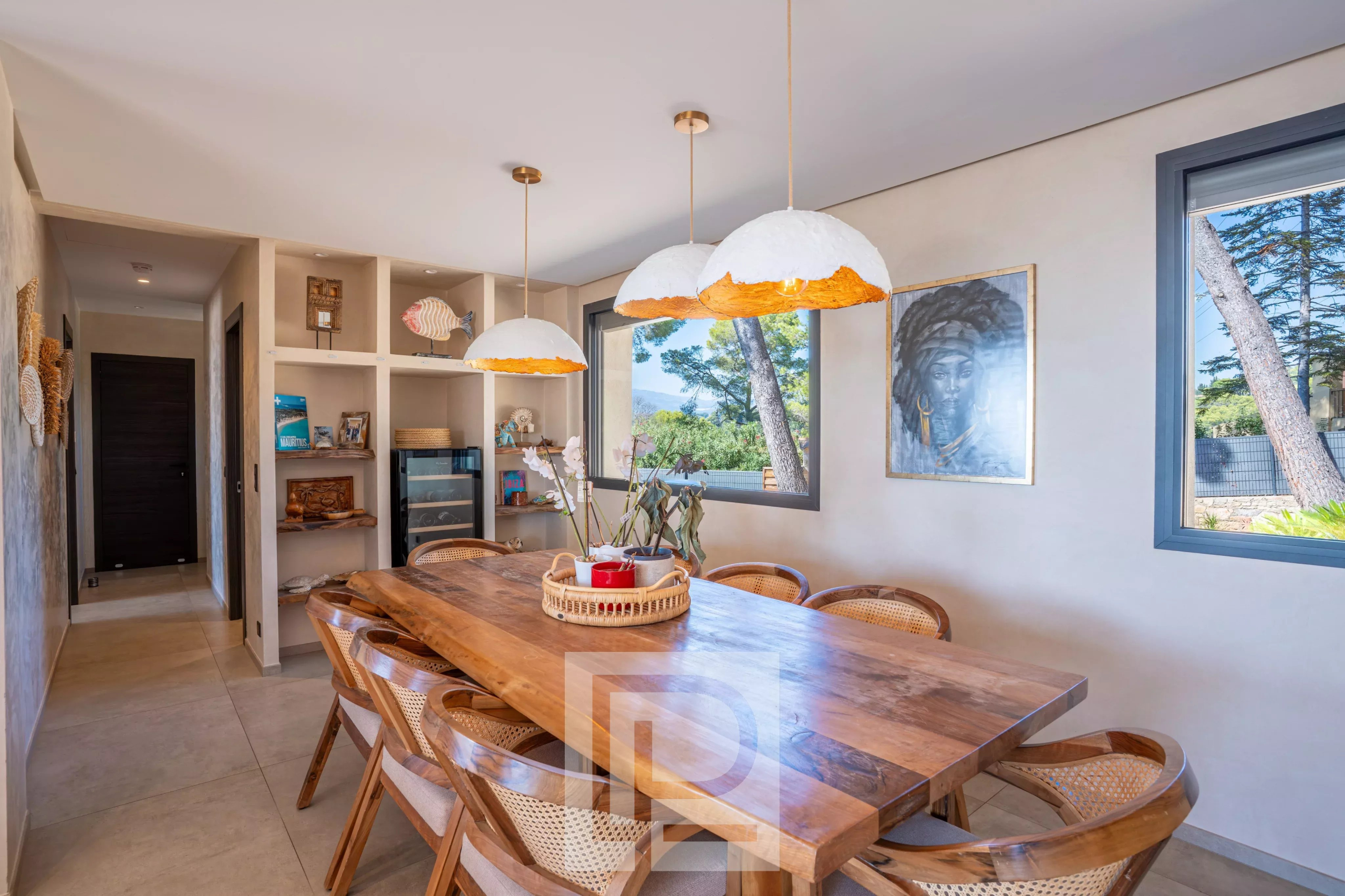 Salle à manger d'une villa rénovée avec table en bois et luminaires modernes.