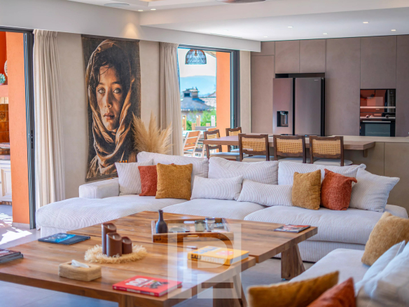 Intérieur d'une villa rénovée avec un grand salon, un tableau sur le mur et une vue sur l'extérieur.