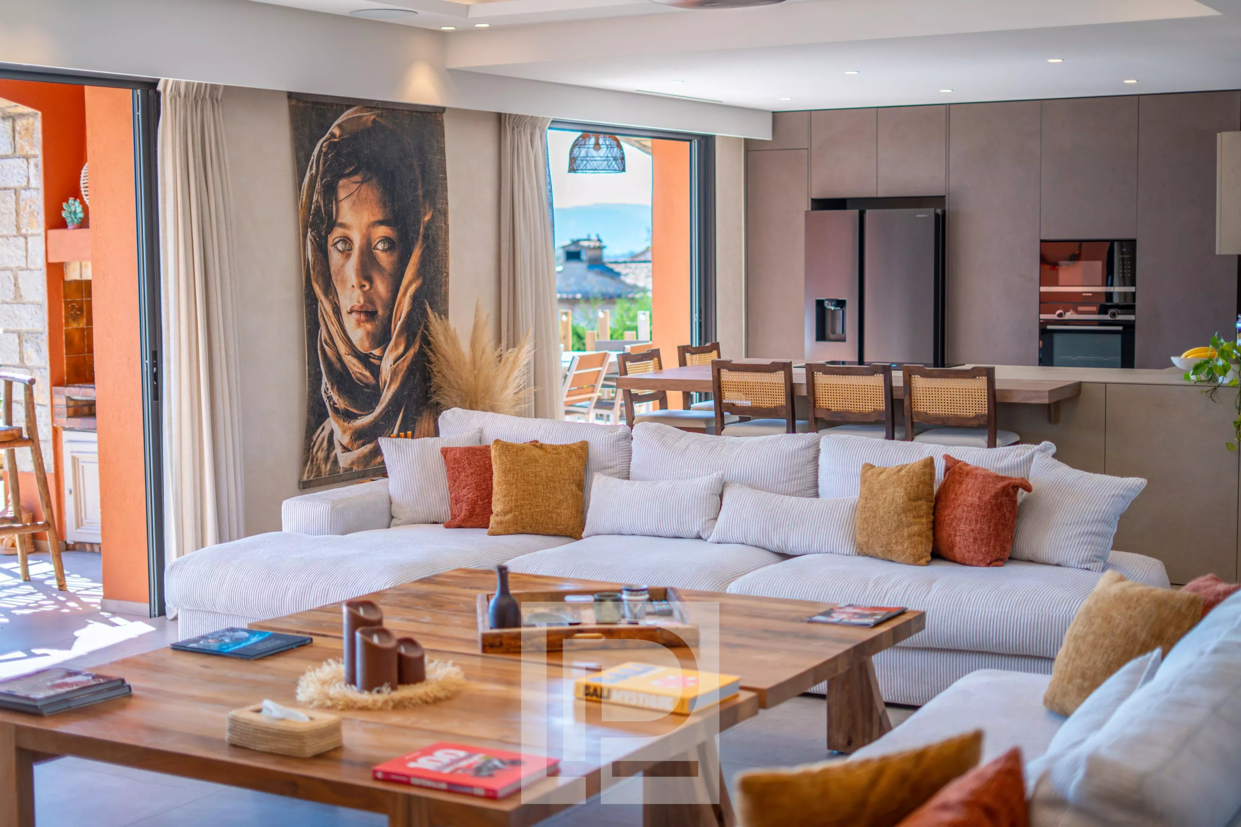Intérieur d'une villa rénovée avec un grand salon, un tableau sur le mur et une vue sur l'extérieur.