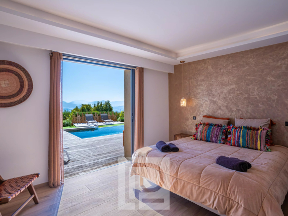 Chambre d'une villa rénovée avec vue sur la mer et accès à la piscine.