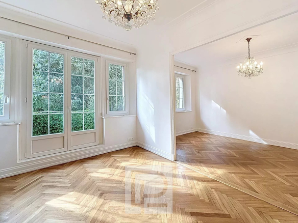 Intérieur d'un appartement rénové avec parquet en bois et grandes fenêtres, lumineux.