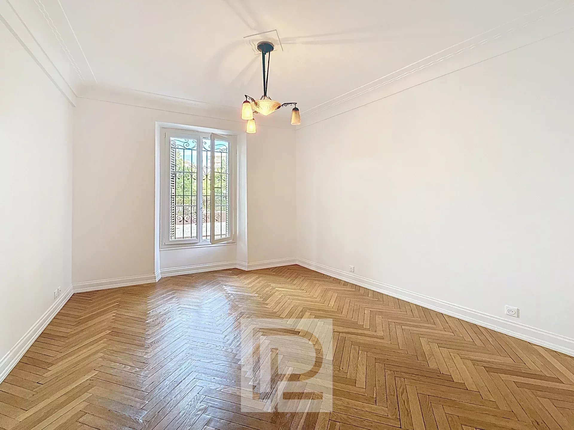Appartement rénové à Cannes Intérieur d'un appartement rénové avec parquet en chevron et fenêtres à petits carreaux.