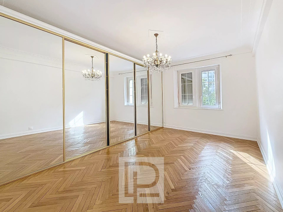 Intérieur d'un appartement rénové avec parquet en bois et miroirs, lumière naturelle.