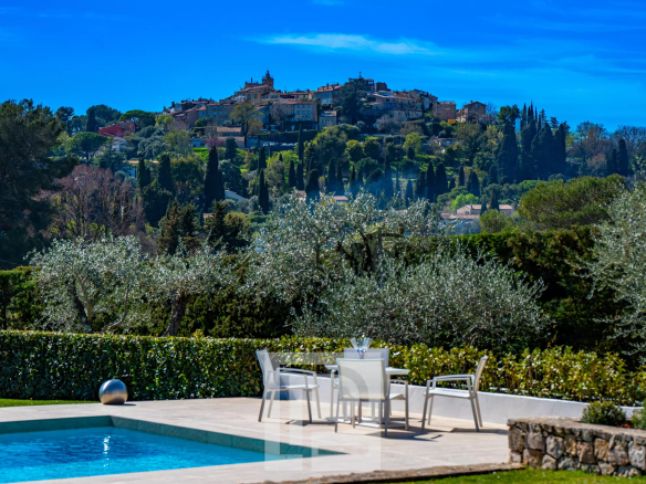 Vue d'une villa californienne avec piscine, surplombant un village historique et des oliviers.