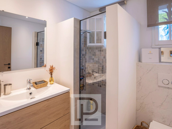Modern bathroom with shower and light wood furniture.