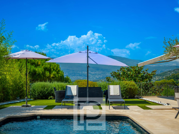 Vue d'une villa provençale avec piscine, parasols et paysage verdoyant à Mougins.