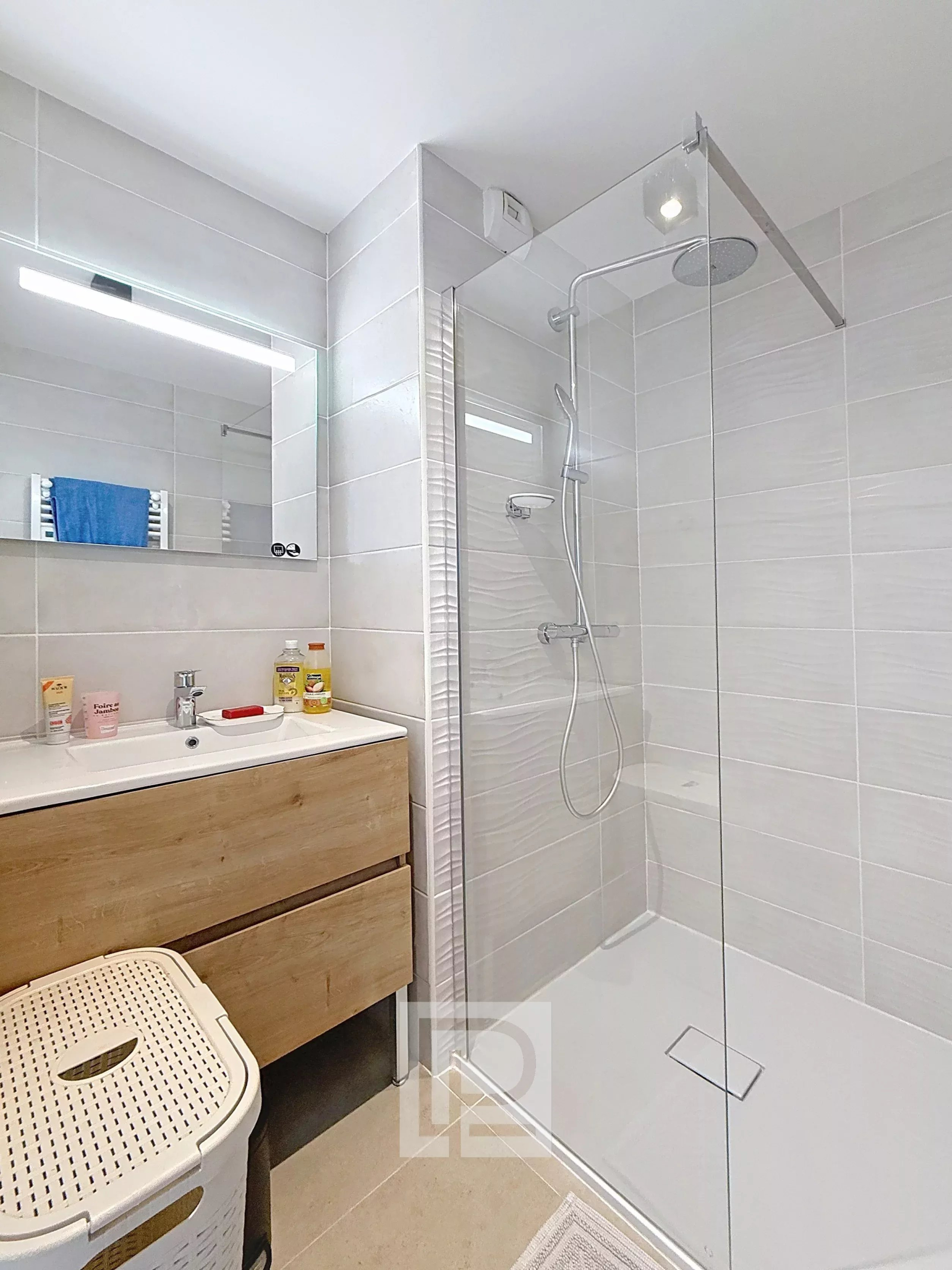Salle de bain d’un appartement à Mougins Salle de bain moderne avec douche à l'italienne et meuble sous vasque en bois.