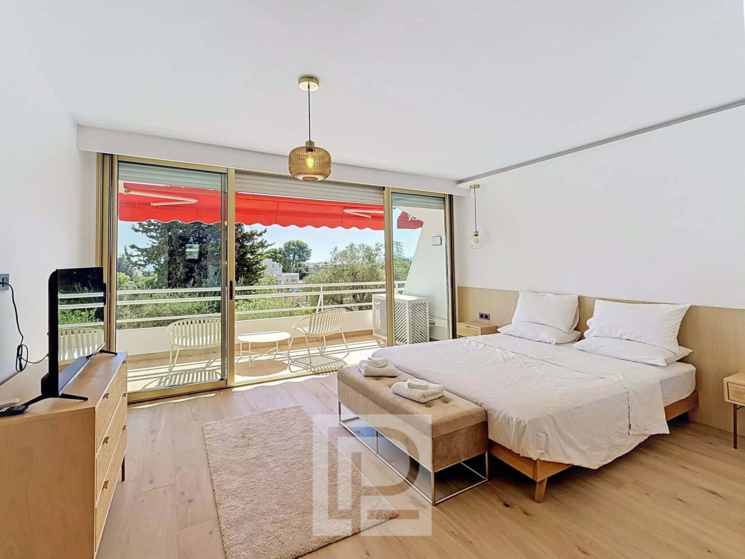 Appartement rénové à Cannes – Secteur Montfleury Chambre d'un appartement rénové avec lit double et balcon à Cannes, secteur Montfleury.