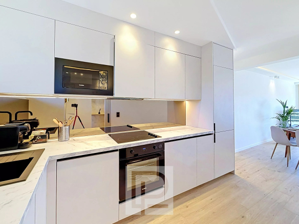 Cuisine moderne d'un appartement rénové à Cannes, avec des meubles clairs et des appareils électroménagers intégrés.