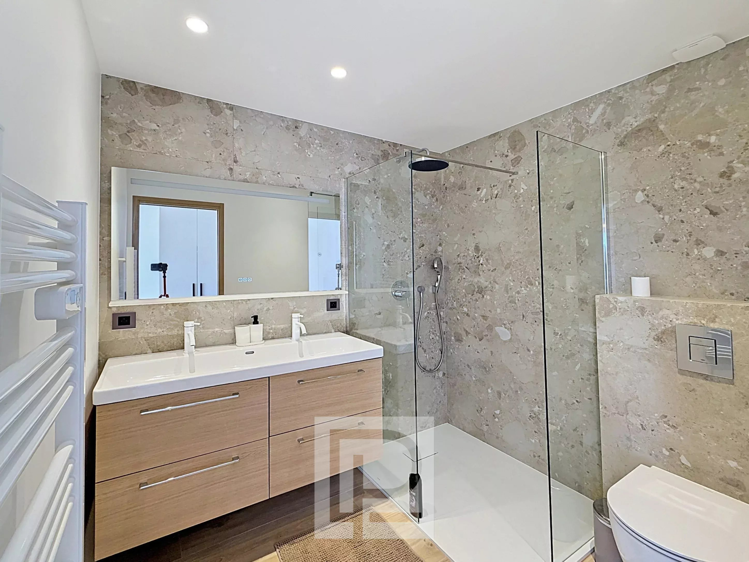 Salle de bain rénovée de l’appartement à Cannes Salle de bain moderne avec douche à l'italienne et double vasque dans un appartement rénové.