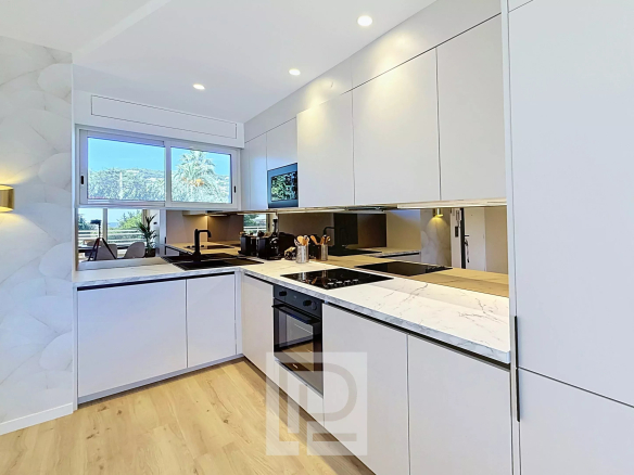 Cuisine moderne d'un appartement rénové à Cannes, avec plans de travail en marbre et équipements récents.