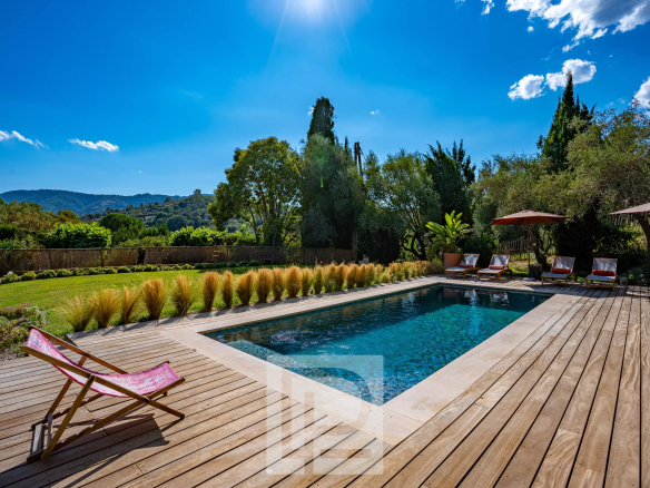 Piscine entourée de chaises longues et de verdure dans une bastide rénovée à Mougins.