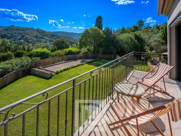 Terrasse d'une bastide rénovée avec vue sur des collines verdoyantes et un jardin.