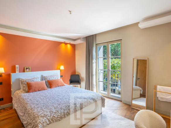 Chambre d'une bastide rénovée avec vue sur un jardin, murs orange et lit double.